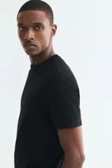 Remera de punto liviano color negro, con cuello redondo y mangas cortas. Diseño slim fit de corte entallado y bajo recto.