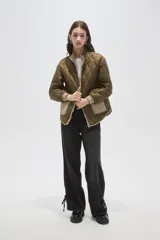 Campera acolchada de poliamida en color beige, con diseño de costuras en rombos, cuello alto, cierre frontal y bolsillos delanteros con solapa.