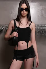 Corset negro de microfibra liviana embutido, con escote recto, recortes y ballenas insertadas en cinta bies. Breteles desmontables con avíos metálicos regulables y embutidos en base. Detalle de avío pasador de marca en terminación inferior con tira elástica y portaligas metálico. Espalda con panal realizado en hilo elástico como ajuste.