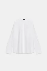 Camisa blanca de manga larga, confeccionada en popelín de algodón 100%. Presenta cuello solapa, cierre frontal de botones y un bolsillo de plastrón en el delantero.