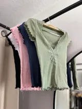 Remera corta color verde agua, con escote en V y detalle de puntilla blanca en el borde.