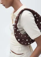 Jersey de punto fino color crema, con cuello polo, cierre frontal con botones, manga corta y diseño entallado con detalle de nudo en la cintura.