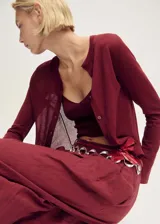 Cardigan de punto fino color bordó, con cuello redondo, cierre frontal de botones y manga larga. Diseño recto y entallado.