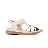 Sandalia de cuero Usaflex modelo Catri, color marfil con suela baja en tono marrón. Presenta diseño de tiras cruzadas en la parte delantera y tira elástica en el empeine.