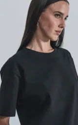 Remera de manga corta y cuello redondo, color negro, confeccionada en algodón premium de tacto suave. Presenta un calce regular con un recorte distintivo en la espalda.