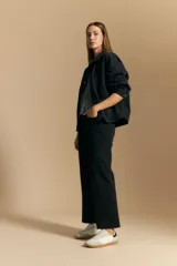 Jean de corte recto y tiro medio, confeccionado en denim elastizado de color negro. Presenta un diseño clásico con cierre de botón y cremallera, bolsillos laterales y traseros, y ruedo con terminación deshilachada.