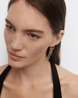 Aro individual dorado con dije colgante de cristal de roca transparente en forma cilíndrica.