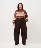 Pantalón de cuero sintético con corte barrel, de tiro alto y pierna ancha con estructura curva. Presenta bolsillos laterales tipo cuchillo y costuras decorativas con pespuntes visibles.