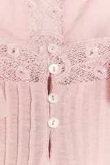 Top sin mangas color rosado pálido, con escote recto y tirantes anchos. Presenta detalles de bordados y encaje en el canesú central y en el ruedo inferior, con un diseño de capas sueltas.