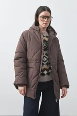 Campera puffer negra con diseño acolchado, capucha integrada y cierre frontal con botones a presión. Presenta puños elásticos y costuras decorativas en el frente.