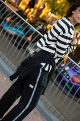 Pantalon de estilo deportivo color negro, con bolsillos laterales tipo cargo y una banda lateral decorativa con inscripciones. Presenta un corte holgado y cómodo.