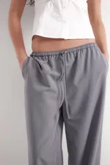Pantalón negro de corte wide leg, con cintura elástica ajustable mediante cordón y bolsillos frontales.