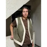 Chaleco estilo gamulán color verde militar con forro y bordes de corderito sintético blanco, diseño sin mangas.