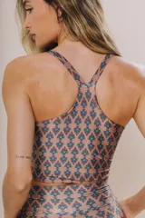 Top deportivo color azul grisáceo con estampado de patrón repetitivo. Presenta escote redondo al frente y espalda con tirantes cruzados en forma de Y, de largo medio.