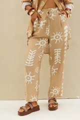 Pantalón beige con estampado en color blanco de motivos abstractos y soles, de corte recto con cintura elástica y cordón ajustable.