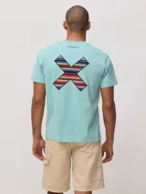 Remera de algodón orgánico color turquesa, con corte regular fit y estampa en la espalda en forma de X con diseño de guardas étnicas multicolores.