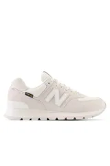Championes urbanos New Balance modelo 574, color beige, confeccionados en una combinación de gamuza y tela técnica Cordura, con el logo N característico en los laterales y entresuela con tecnología ENCAP.