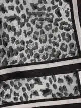 Pañuelo cuadrado de seda con estampado de girasoles en un jarrón. Tiene un borde amarillo con un patrón decorativo.