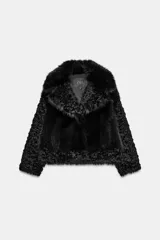 Abrigo corto de Zara Woman Collection con cuello de solapa y manga larga. Presenta una combinación de texturas con aplicación de pelo sintético y diseño de efecto rizado en mangas y bordes. Cuenta con forro interior y cierre frontal mediante ganchos metálicos.