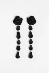 Pendientes largos de diseño colgante, compuestos por una pieza superior en forma de rosa y una serie de elementos en forma de gota, todos con acabado aterciopelado negro.