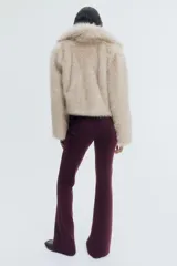 Pantalón de tiro alto confeccionado en punto roma, con diseño ajustado en la parte superior y piernas acampanadas. Presenta bolsillos insertados decorativos en la parte frontal.