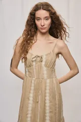 Vestido largo negro de algodón, con breteles finos, escote con frunce y lazo regulable. Tiene cintura definida y falda amplia escalonada, con detalles bordados verticales en contraste.