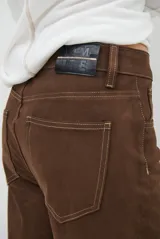 Pantalón de corte recto confeccionado en gamuza color marrón, con costuras a la vista en tono contrastante y diseño de paneles horizontales en las piernas.