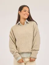 Buzo de punto color beige, con cuello redondo, mangas largas y puños acanalados. Presenta un diseño holgado y textura suave.