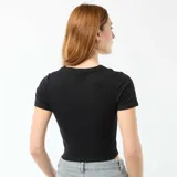 Camiseta crop de corte ajustado, color negro, con cuello redondo y mangas cortas.