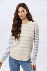 Buzo tejido de algodón con diseño a rayas horizontales, cuello redondo y mangas largas. El cuerpo presenta rayas en tonos azul y beige, mientras que las mangas combinan rayas en tonos azul y rosado.