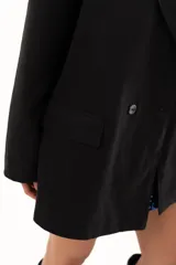 Blazer negro de corte oversize con solapas clásicas, cierre frontal de doble botonadura y bolsillos laterales con solapa.