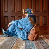 Mochila de símil cuero color marrón, con apertura superior, dos bolsillos frontales con cierre metálico y bolsillos laterales. Incluye tres bolsillos internos y correa extraíble.