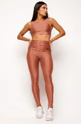 Top deportivo color terracota, de corte crop y manga sisa, con cuello redondo y espalda escotada. Presenta textura acanalada y acabado brillante.