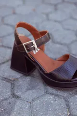Sandalias de cuero color chocolate con plataforma y tacón cuadrado. Tira ancha sobre los dedos y tira con hebilla al tobillo.