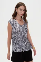 Blusa de poliéster con estampado geométrico en tonos azul y blanco, diseño plisado, corte holgado, mangas cortas y cuello a la base.