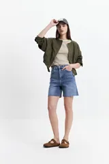 Campera verde militar sin cuello, con elástico y cinto regulable en la cintura, bolsillos amplios y cierre frontal.