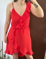 Vestido corto rojo con volados en el escote y la falda, de corte asimétrico y tirante fino en un hombro.