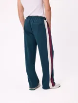 Pantalón tipo babucha de la marca Rusty, color azul petróleo con franjas laterales en color bordó. Presenta cintura elástica con cordón ajustable y logo bordado en la pierna izquierda.