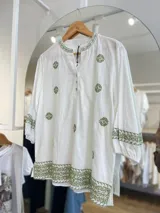 Blusa blanca de manga 3/4 con bordados en hilo verde oliva, cuello mao con abertura y botones, y terminación bordada en el ruedo y puños.