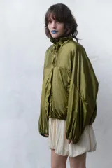 Chaqueta de nylon con acabado satinado, diseño oversize, cuello subido ajustable con cordones, cierre frontal con botones, mangas largas con puños elásticos y bajo con elástico.