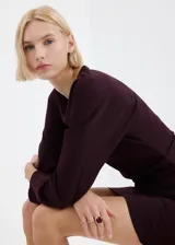 Vestido corto color bordó, de manga larga con puños sutilmente abullonados, escote bote y diseño estructurado.