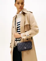 Cartera tipo mensajera de forma rectangular, con solapa frontal y correa ajustable. El cuerpo del bolso está confeccionado en jacquard con un patrón repetitivo del monograma TH en tonos negro y gris oscuro. Posee una insignia metálica dorada con el logo TH en el centro de la solapa.