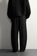 Pantalón de corte relajado confeccionado en tejido de algodón, con cintura elástica y detalle de pliegues estructurales en las perneras. Cuenta con bolsillos frontales y un bolsillo trasero de plastrón.
