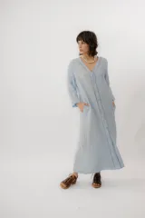 Vestido largo de lino color tostado, de manga larga, con escote redondo y diseño amplio y fresco. Cuenta con un delicado bordado en la espalda con motivos marinos y la frase "no se lo digas".