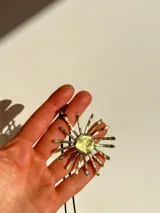 Collar con dije dorado en forma de sol con rayos texturizados y cordón negro.