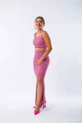 Pollera midi de tejido de punto con diseño acanalado diagonal, tiro alto y tajo lateral profundo. Presenta un acabado con flecos en el ruedo.