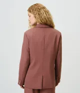 Blazer de sastrería color marrón, de modelaje comfort, corte estructurado y largo medio. Cuenta con cuello con solapa, cierre frontal de botón único, bolsillos con tapa y mangas largas.