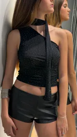 Top negro de un solo hombro con apliques de strass y detalle de bufanda o lazo incorporado al cuello.