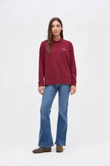 Remera tipo polo de manga larga en color bordó, confeccionada en algodón pesado con textura suave. Presenta cuello clásico con botones, puños en las mangas y un pequeño bordado en el pecho.