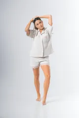 Conjunto de pijama de tela waffle color crema, compuesto por una camisa de manga corta con botones, bolsillo y detalle de broderie, y un short con elástico y cordón en la cintura con terminación de broderie.